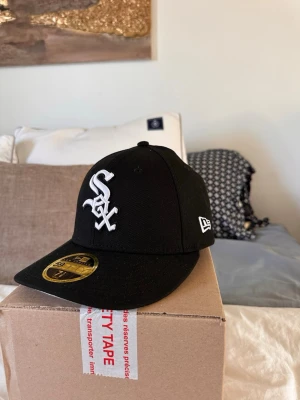 Svart New Era White Sox keps - Fick hem denna idag och insåg att den var för liten. Vill prova att sälja den först då det kostar 200kr att skicka den tillbaka😅 den är slutsåld överallt. Så ta den för 400kr prutat och klart. Stl 7 1/8 - 56,8 cm. Snygg svart keps från New Era med White Sox-logga broderad i vitt framtill och New Era-logga på sidan. Klassisk 59FIFTY-modell med böjd skärm och strukturerad passform. 