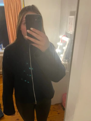 Mörkblå ribbad ziptröja med hög krage - Mysig mörkblå ribbstickad tröja med dragkedja framtill och hög krage. Tröjan har långa ärmar och en avslappnad passform, perfekt för lager på lager. Passar till både jeans och leggings för en chill look. Något nopprig i materialet 