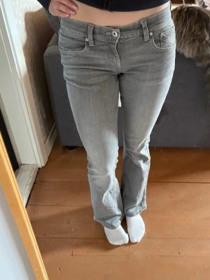 Grå bootcut jeans med broderade fickor - Säljer ett par grå bootcut jeans med snygga broderade detaljer på fickorna. De är i storlek 38 men passar 36 också!
