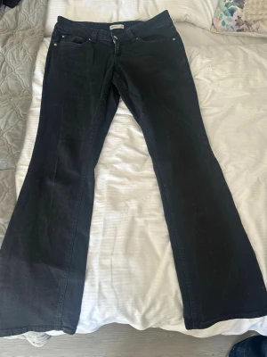 Svarta bootcut jeans med fickdetaljer - Snygga svarta bootcut jeans från Gina med klassiska fem fickor och silverfärgade knappar på bakfickorna. Jeansen har låg midja och är tillverkade i ett mjukt denimtyg som ger en skön passform. Perfekta för dig som gillar en retroinspirerad look. Ser lite använd ut på fickorna men har bara använt dom 4 gånger som max så dom e nästan helt nya köpte dom för ca 400. Och dom e för stora. Pris kan diskuterars 