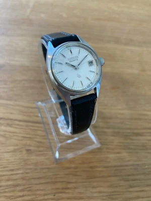 Citizen CQ Quartz 24mm Damklocka - Vintage inspirerad (70/80-tal) Citizen Quartz damklocka med datumvisning och självlysande. Klockan har ett svart läderarmband och en boett i stål. Urtavlan är vit med silverfärgade index och visare. Fint skick enligt bilder. Japanskt kvalitetsurverk. Modellnummer: 10284782, 47-2018. Behöver bara nytt batteri.  Begagnat värde: < 1700 SEK Mitt pris: 689 SEK  Skickas snabbt och spårbart. Skriv vid frågor och se gärna mina andra annonser!