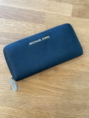 Michael Kors plånbok Svart - Svart Michael Kors plånbok med dragkedja. Plånboken har flera fack för kort och sedlar samt ett myntfack med dragkedja. Skick enligt bilder.  Värde: 250 SEK Mitt pris: 189 SEK  Skickas snabbt. Se gärna mina andra annonser!