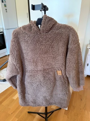 Fluffig tröja med luva  - Brun fluffig tröja med luva, står ingen storlek men kanske en L? Märket fashion friends. Ny. 