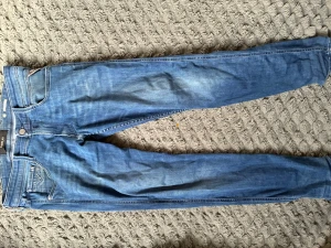 Blå slim fit jeans från replay - Snygga blå slim fit jeans från replay med klassisk femficksdesign och diskreta slitningar framtill. Jeansen har dragkedjegylf och detaljerade bakfickor med broderi. Perfekta för en avslappnad och trendig stil.