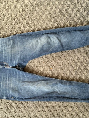 Blå skinny jeans Tiger of Sweden - Säljer ett par klassiska blå skinny jeans från Tiger of Sweden. Jeansen har fem fickor, dragkedja och knapp i midjan samt snygga slitningar och ljusare partier på benen. Perfekta för en trendig och avslappnad look.