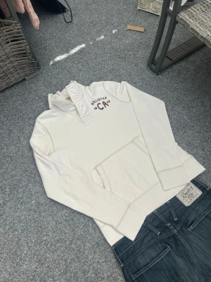 Hollister vit hoodie – clean streetwear / y2k vibe - Vit hoodie från Hollister i storlek M 🤍  Riktigt clean och minimalistisk hoodie som passar perfekt för en streetwear / casual outfit. Gjord i 100% bomull vilket gör den skön och andningsbar – perfekt för både vardag och chill fits.  Har snygga detaljer som knappar vid kragen, broderad logga och klassisk kangaroo pocket. Ger en riktigt nice basic men trendig vibe med lite vintage/Y2K känsla.  Lätt att matcha med jeans, cargos eller sweatpants för en komplett clean fit.  Skick: Bra skick, normalt 