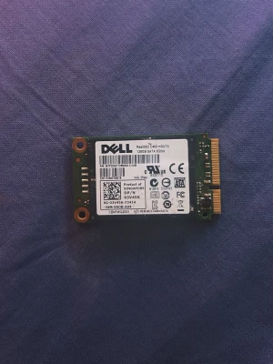 Dell mSATA SSD 128GB - Säljer en kompakt mSATA SSD från Dell med 128GB lagringsutrymme. Perfekt för uppgradering av laptop eller annan dator. Svart och grön kretskort med vit etikett och guldiga kontakter. Passar till de flesta enheter med mSATA-stöd.
