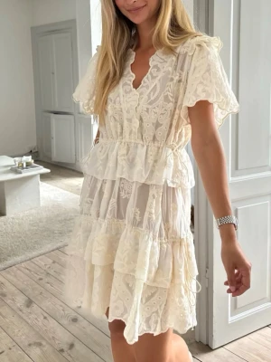 BYIC klänning i stl S helt ny studentklänning - Kort spetsklänning med unik vintagelook, volangdetaljer. Djup halsringning vid bröstet. Möjlighet till justering i midjan och i nedre delen av klänningen.  Helt ny