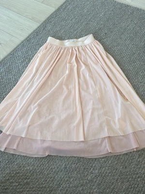 Ljusrosa långkjol med volang - Säljer en ljusrosa långkjol från bikbok med volangdetalj och elastisk midja. Kjolen har ett tunt, flowigt material som ger en snygg och luftig look. Perfekt för dig som gillar en feminin och soft stil.