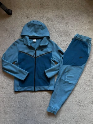 Nike Tech Tracksuit  - Sällsynt blå Nike tech i storlek S. Köpt för några år sedan på JD, men är i väldigt bra skick då den endast är använd ett par gånger. För mer frågor eller bilder är det bara att skriva. 