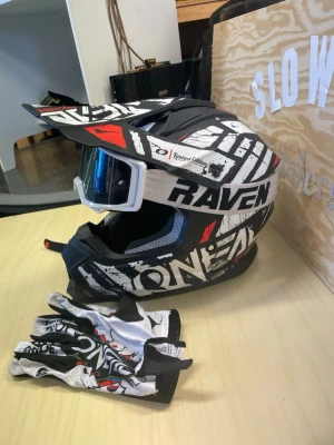  crosshjälm och handskar - Säljer en svartvit O'Neal crosshjälm med Raven glasögon, ungefär helt ny Hjälm inte en skroma, luktar som ny så väldigt snålt använd. Handskarna ingår strl XXL. 