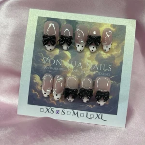 MuseNoir (S);Medium Almond - Handgjorda press-on naglar i nude med ljusrosa french och svarta detaljer, dekorerade med 3D svarta rosetter och svarta prickar. Naglarna har en medium lång almond form och coolt handmålat mönster som ger en unik look. Perfekt för dig som vill sticka ut med snygga detaljer.