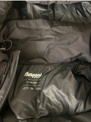 Svart pufferjacka från Bergans XS - Säljer en svart pufferjacka från Bergans of Norway i storlek XS. Jackan har huva, dragkedja framtill och är tillverkad i ett slitstarkt, vadderat material som håller dig varm under kalla dagar. Perfekt för vintern och riktigt snygg streetstil.