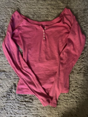 Rosa långärmad topp Brandy Melville - Säljer en superfin rosa långärmad henley topp från Brandy Melville. Den har en smickrande passform och fina knappar framtill som ger en lite mer detaljrik look. Endast använd en gång, så den är i nyskick utan fläckar, noppor eller andra tecken på användning. Storlek: One size (passar som S) Färg: Rosa Perfekt både till vardags med jeans eller uppklätt med kjol – en riktigt användbar basic i garderoben 💕
