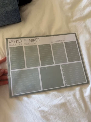 Grå Weekly Planner i plast - Snygg och praktisk weekly planner i grått med vita rutor för varje veckodag, helg, anteckningar och to-dos. Planeraren är laminerad och kan användas med whiteboardpenna. Perfekt för att hålla koll på veckan och organisera vardagen.