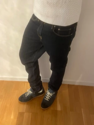 Mörkblå jeans med kontrastsömmar - Snygga mörkblå jeans med raka ben och tydliga kontrastsömmar. Klassisk femficksmodell och normal midja. Perfekta för en avslappnad och trendig look.