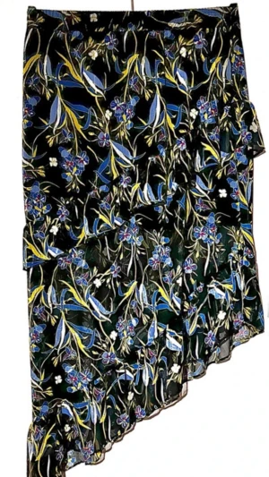 Gestuz Ebony Skirt stl 40 – Blommig Asymmetrisk Lyxkjol - Säljer en fin kjol från det danska designmärket Gestuz, modell Ebony skirt. Kjolen har en unik asymmetrisk skärning med vackra volanger. Midjan har en bekväm resår vilket gör att den sitter perfekt. Kjolen är av hög kvalitet med ett yttertyg i skir chiffong och innerfoder i 100%viskos. kjolen faller fint utan att vara genomskinlig. Märke:Gestuz Storlek: 40 Material: 100% Polyester (Yttertyg), 100% Viskos (Foder) Midja (halvt mått):ca 40cm Längd innekjol:ca 44cm Längd: ca 65cm Längd: ca 106cm