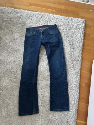 Mörkblå bootcut jeans 33/36 - Snygga mörkblå bootcut jeans med klassisk femficksdesign och normalhög midja. Storlek 33/36 Jeansen har raka ben och är tillverkade i denim med lätt stretch för extra komfort. Perfekta för en avslappnad och trendig look. Hör av dig vid minsta fundering. 