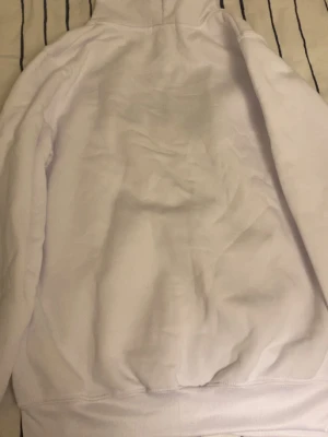 Vit hoodie från Polo Ralph Lauren - Snygg vit hoodie från Polo Ralph Lauren med dragkedja framtill och klassisk huva med vita snören. Ikoniska Polo-loggan broderad på bröstet. Mjuk bomullskvalitet som är skön att ha på sig. Perfekt för en clean och stilren look.