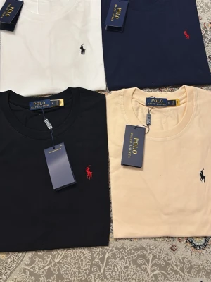 Klassisk t-shirt från Polo Ralph Lauren - Snygg t-shirt från Polo Ralph Lauren med broderad logga på bröstet. Finns i flera färger: vit, marinblå, svart och beige. T-shirten har rund halsringning och korta ärmar, tillverkad i mjuk bomull för en skön känsla.