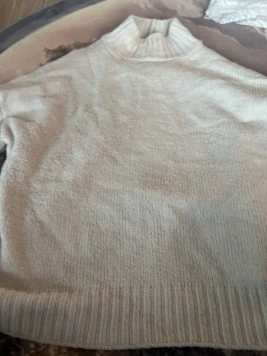 Vit stickad polotröja från NAKD - Säljer en vit stickad polotröja från NAKD i storlek XXL. Tröjan har en hög ribbad krage och ribbade muddar vid ärmslut och nederkant. Perfekt för kalla dagar och enkel att matcha med olika outfits.