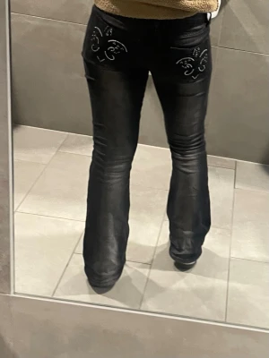 Svarta bootcut jeans med brodyr från Gina Tricot - Säljer ett par low waist svarta bootcut jeans med snygg brodyr på bakfickan. Jeansen är knappast använda eftersom jag inte föredrar bootcut på mig, men supersnygg modell med lätt utsvängda. De är i storlek 170 men passar mig perfekt som är xs/s.