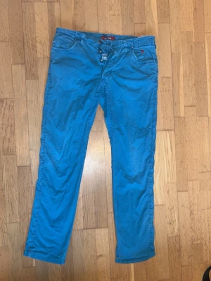 Jaggy Chinos - ljusblå/turkos - Snygga blå chinos med rak passform från Ralph Lauren. Byxorna har klassiska fickor fram och bälteshällor. Perfekta för dig som vill ha en färgstark och avslappnad stil.