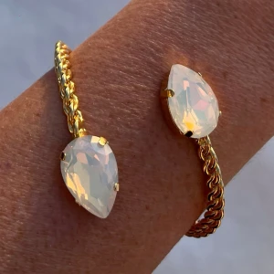 Armband Bangle White Opal - Armband, Bangle, i guldpläterad mässing med kristaller. Kristaller Pear 18mm. Färg White Opal, ställbar storlek. De senare bilderna andra armband som finns i lager. Jag skickar endast spårbart, samfraktar. Fast pris. Besök gärna mina övriga annonser.  Till mina smycken använder jag kristaller från Preciosa, Aurora och Swarowski.