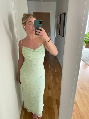 Ljusgrön långklänning med smala axelband - Snygg ljusgrön långklänning från Gina tricot. Klänningen har en lätt draperad urringning och figurnära passform. Använd 2 gånger