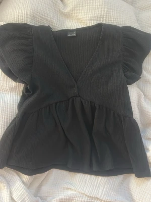 Svart v-ringad blus från Gina Tricot - Supersöt svart blus från Gina Tricot med v-ringning och puffiga korta ärmar. 