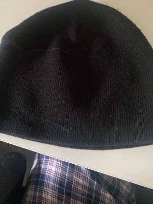 Svart ribbad mössa från H&M - En enkel och stilren svart mössa från H&M. Mössan är ribbstickad och har en klassisk, rundad form som passar till det mesta. Perfekt för att hålla värmen under kyliga dagar.