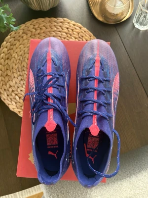 Blå och rosa Puma fotbollsskor - Säljer ett par snygga fotbollsskor från Puma i blått och rosa med vita detaljer. Helt oanvända i storlek 43 