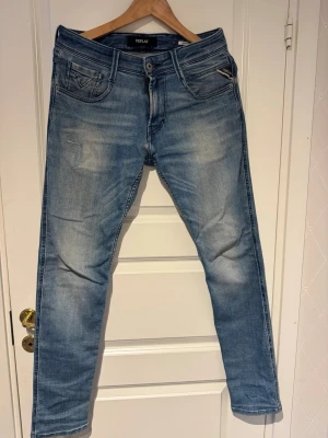Ljusblå Replay anbass - Snygga ljusblå jeans från Replay med klassisk femficksdesign och diskreta slitningar framtill. Jeansen har raka ben och är tillverkade i bomull med en liten mängd stretch för extra komfort. Perfekta för en avslappnad och trendig look.