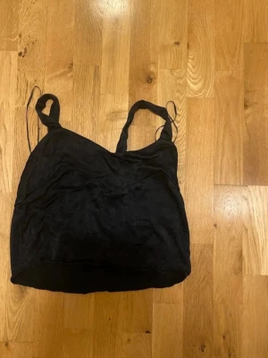 Zara Svart linnetopp med smala axelband stl M - En svart linnetopp med smala axelband och enkel design. Toppen har en lätt croppad passform och är perfekt för att styla lager på lager eller till jeans. Materialet känns mjukt och följsamt mot huden.