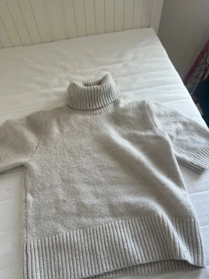 Beige stickad polotröja med kort ärm - Säljer en beige stickad polotröja med korta ärmar och bred ribbstickad kant vid hals, ärmslut och nederkant. Tröjan har en oversized känsla och är perfekt för lager-på-lager. Supermjuk och stilren design. Köpt i Italien så vet inte om den säljs på hm här i Sverige 