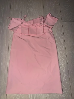 Rosa axelbandslös volangklänning - Söt rosa klänning med volangdetalj upptill och smala axelband. Klänningen är axelbandslös med en rak passform och slutar ovanför knäna. Perfekt för sommarens alla tillfällen.