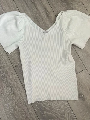 Vit ribbad topp med puffärm från ONLY - Superfin vit ribbad topp från ONLY med v-ringning och trendiga puffärmar. I storlek 146-152 men är stor så är som en xxs/xs. Nästan aldrig använd