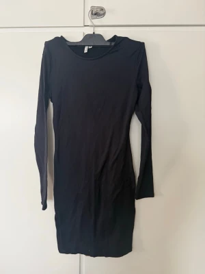 Svart ribbad klänning från NLY Trend - En svart, ribbad och figurnära klänning från NLY Trend. Klänningen har lång ärm, rund halsringning och är i kort modell. Perfekt för dig som gillar en enkel men stilren look.