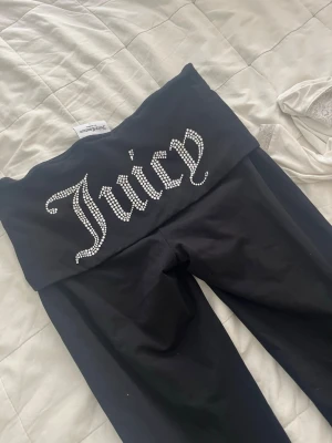 Juicy Couture leggings S - Svarta leggings från Juicy Couture med bred midja och glittrande strasstexten 'Juicy' på baksidan. Stretchigt material som sitter tajt och bekvämt. Perfekta för en trendig och avslappnad look.