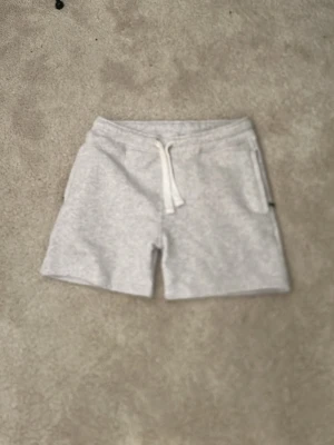 Russemerch shorts grå - Gråa mjukisshorts i bomull med dragsko i midjan och fickor på sidorna. Perfekta för chill dagar eller träning. Inga hål eller liknande som är heller knappt använda. Storlek M