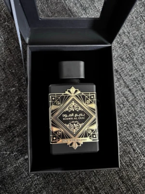 Badee Al Oud Oud For Glory parfym - Helt ny, aldrig använt den.vExklusiv parfym från Lattafa, Badee Al Oud Oud For Glory. Flaskan är svart med guldfärgade orientaliska mönster och text. Kommer i en elegant svart förpackning med fönster. Doften har tydliga oud-noter och flaskan har en lyxig, modern design.