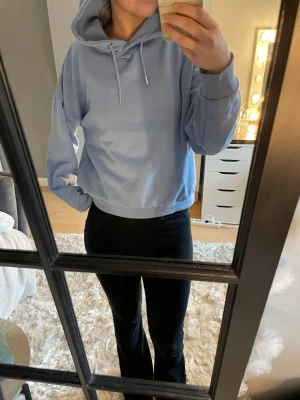 Ljusblå hoodie med huva - Säljer en ljusblå hoodie med huva och dragsnören. Hoodien har en avslappnad passform, ribbade muddar vid ärmslut och nederkant samt är tillverkad i mjukt material. Perfekt för en chill och bekväm stil. Ej haft länge, M sitter som S/M. Ej bra pris,, skriv