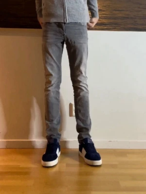 Jack & Jones jeans - Säljer ett par grå slim fit jeans med klassisk femficksmodell och dragkedjegylf. Jeansen har en snygg tvättad look och smal passform som sitter tajt längs benen. Perfekta för dig som gillar en modern och stilren stil. Storlek 28/30