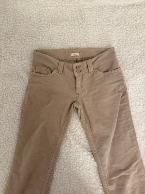 Beige manchesterbyxor från NELLY - Snygga beige corduroy jeans från  NELLY med klassisk femficksmodell och raka ben. Byxorna har dubbla knappar i midjan och coola broderade detaljer på bakfickorna. Tillverkade i mjuk manchester som ger en retrovibe och passar perfekt till en avslappnad stil.