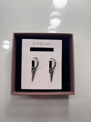 Silvriga örhängen från Edblad - Snygga silvriga örhängen från Edblad med modern design. Helt nya! Super fina, men valde att byta till guld när jag fick dom, rekommenderar verkligen!