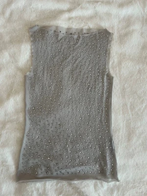 Topp med strassdetaljer - Superfin topp med glittriga strassdetaljer. Materialet är genomskinligt så går att ha ett linne under