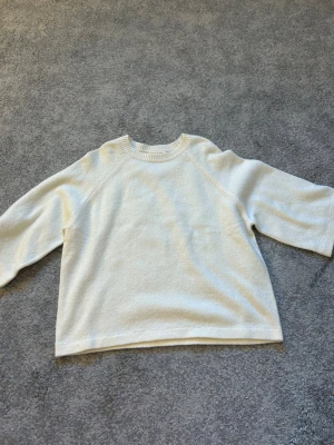 Vit stickad tröja från Ullared  - Klassisk vit stickad tröja från Ullared med rund halsringning och ribbade muddar. Tröjan har en rak passform och trekvartsärmar, vilket ger en avslappnad och stilren look. Perfekt att matcha med jeans eller kjol.