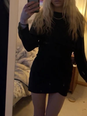 Svart långärmad kortklänning - Snygg svart kortklänning med långa ärmar och rund hals. Klänningen har en enkel och stilren design som passar perfekt till många olika tillfällen. Tillverkad i ett mjukt material som sitter bekvämt på kroppen.