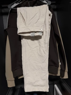 Beiga raka jeans från H&M - Snygga beiga jeans från H&M med rak passform och klassisk femficksdesign. Jeansen har bälteshällor och knappgylf. Perfekta för en clean och avslappnad stil. Materialet känns mjukt och bekvämt, och färgen är lätt att matcha med olika outfits. OBS!!! Kolla sista bilderna lite defekt på byxorna då det ej går bort från tvätt! Storlek w30 L30