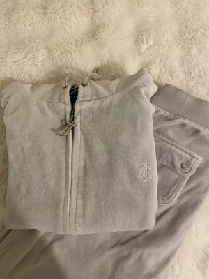 Juicy Couture set - Ljusgrå Juicy Couture set, denna färg säljs inte längre. Det finns endast en missfärgning på insidan av byxan men det är inget som syns. Både byxan och koftan är i xs